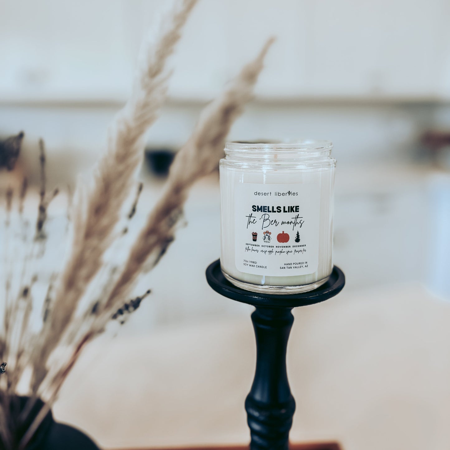 Candle on a black holder with decorative elements in the background