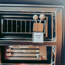 Load image into Gallery viewer, Car air freshener with 'Luxury' branding in a car's air vent.
