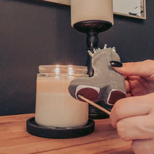 Load image into Gallery viewer, Hands holding a match and striking the bottom of a cowboy boot matchstick holder with a candle lit