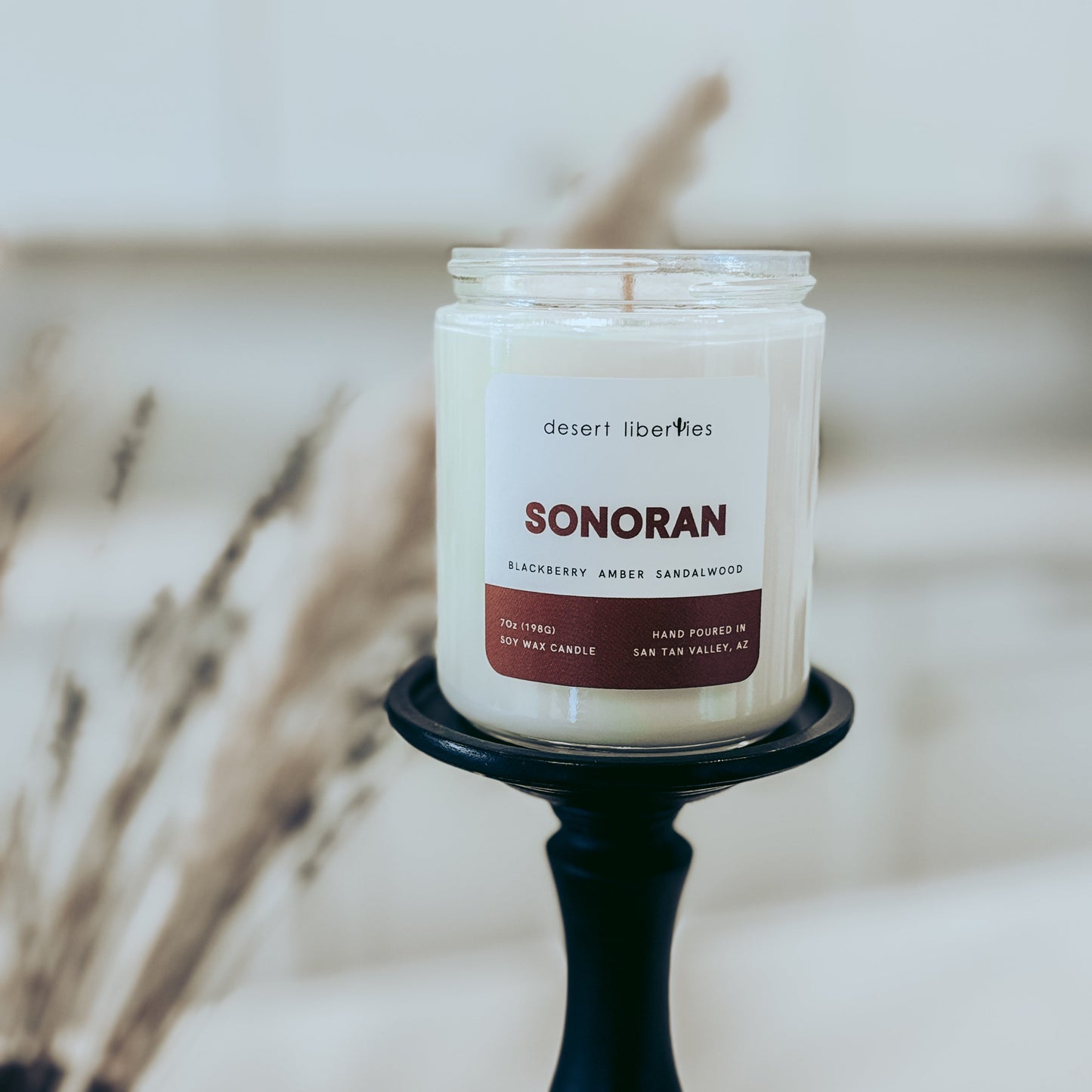 Candle labeled 'Sonoran' on a black holder with a blurred background