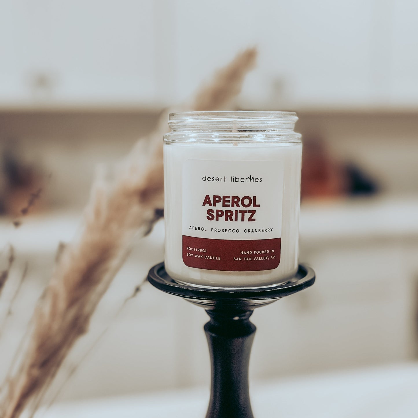 Candle labeled 'Aperol Spritz' on a decorative stand with a blurred background
