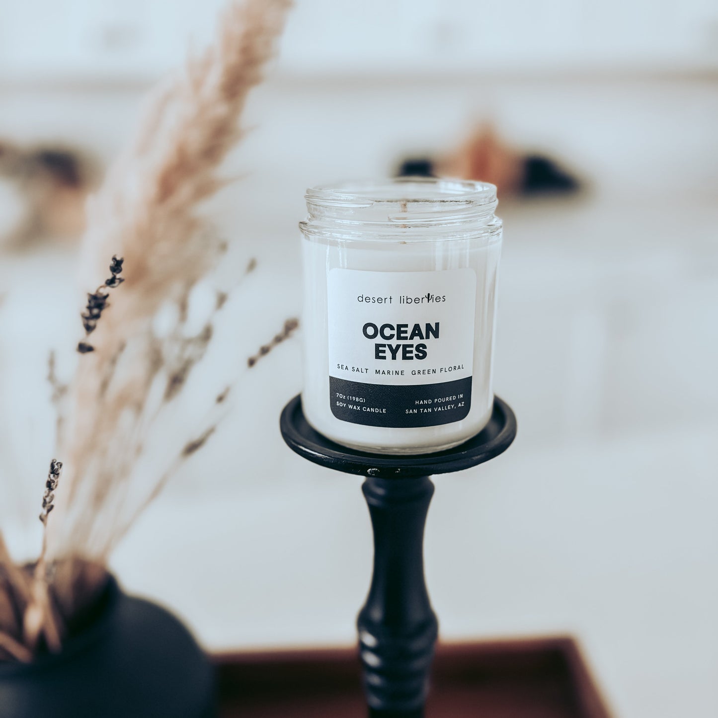 Candle labeled 'Ocean Eyes' on a black holder with a blurred background