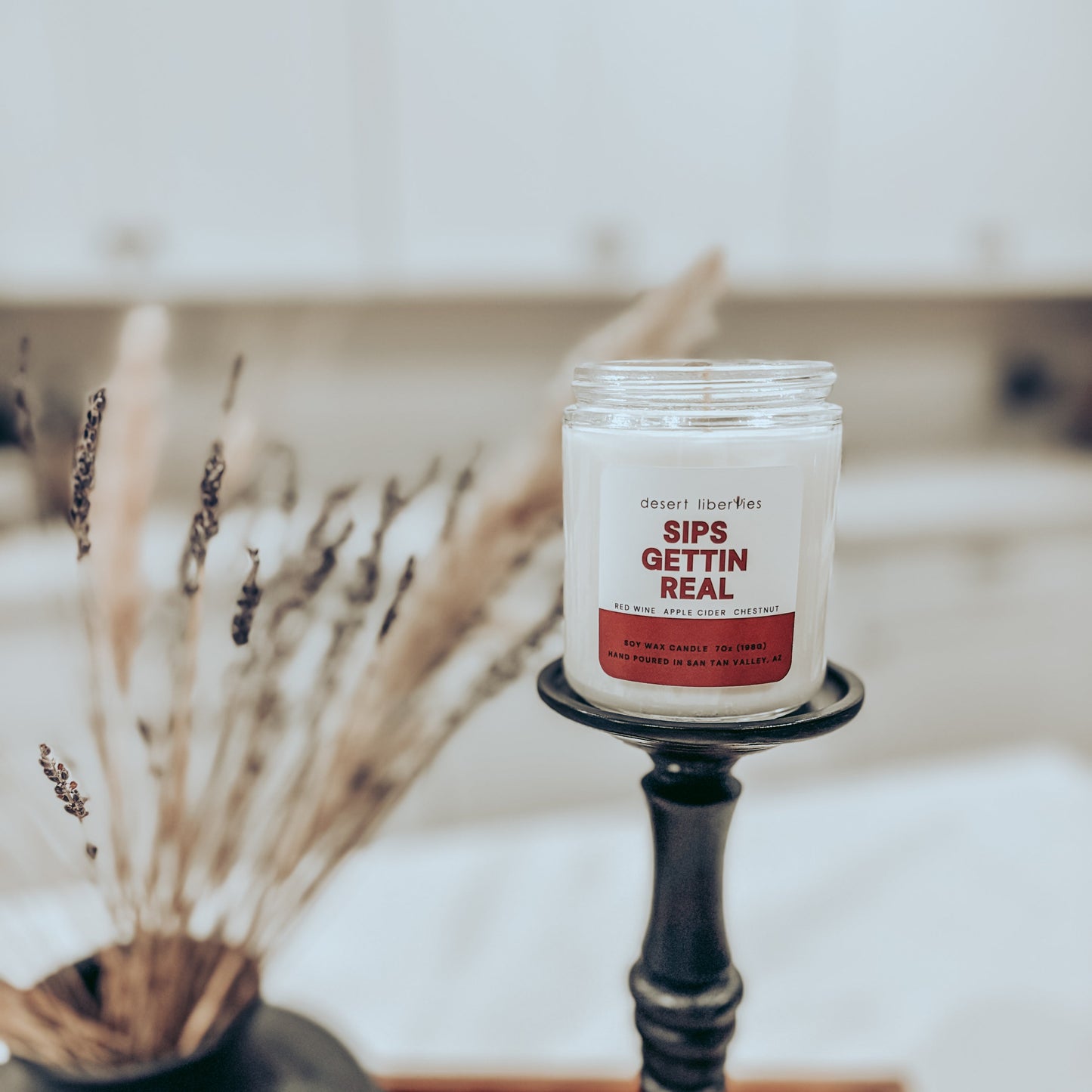Candle on a black holder with a red label in a kitchen setting