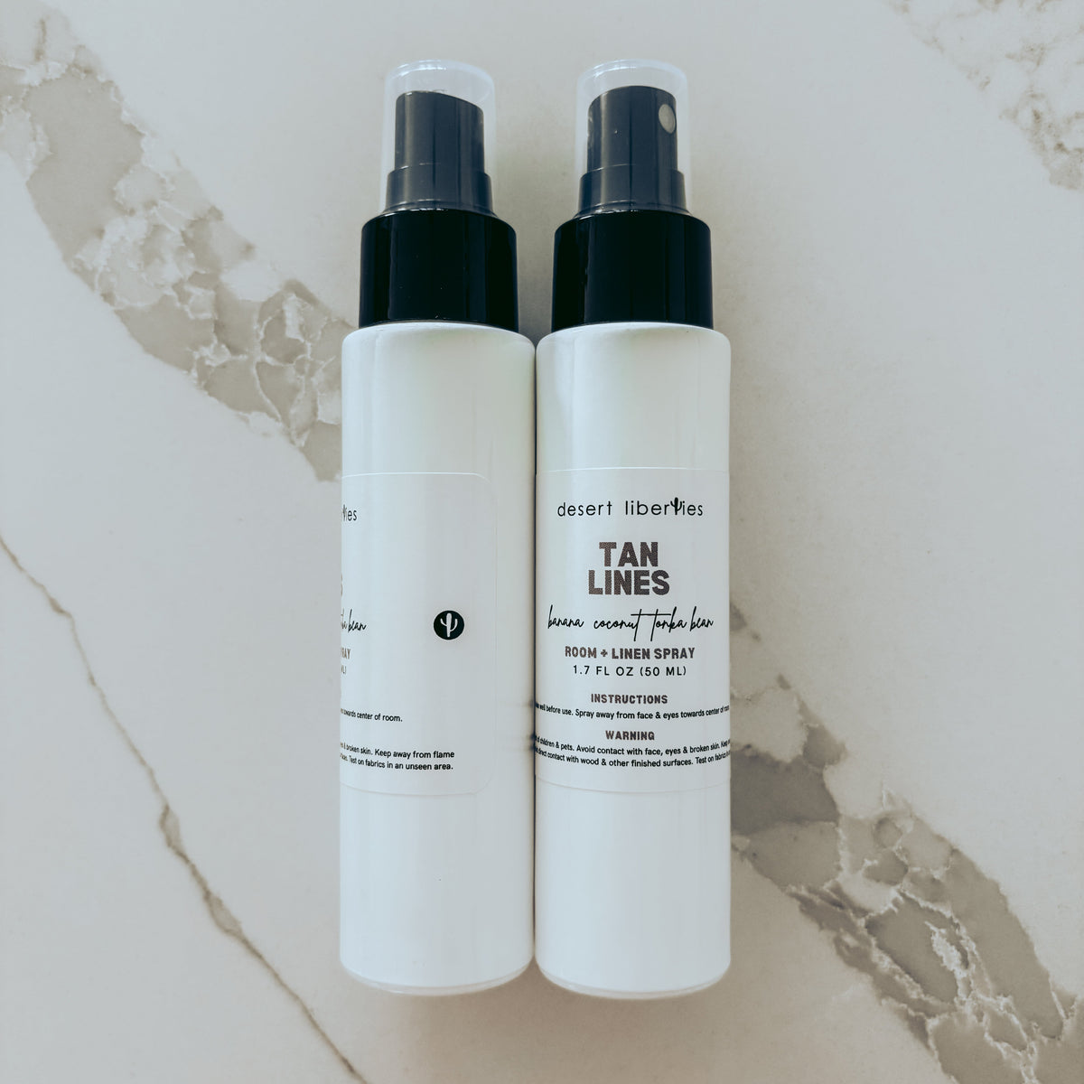 Two white spray bottles with black nozzles on a marble surface