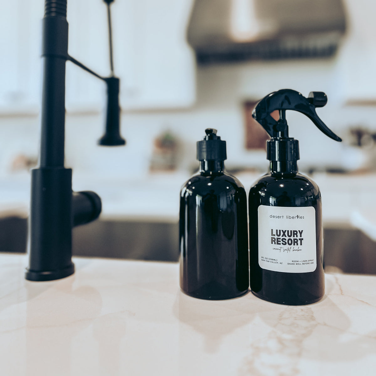 Two black bottles with spray nozzles on a kitchen counter.