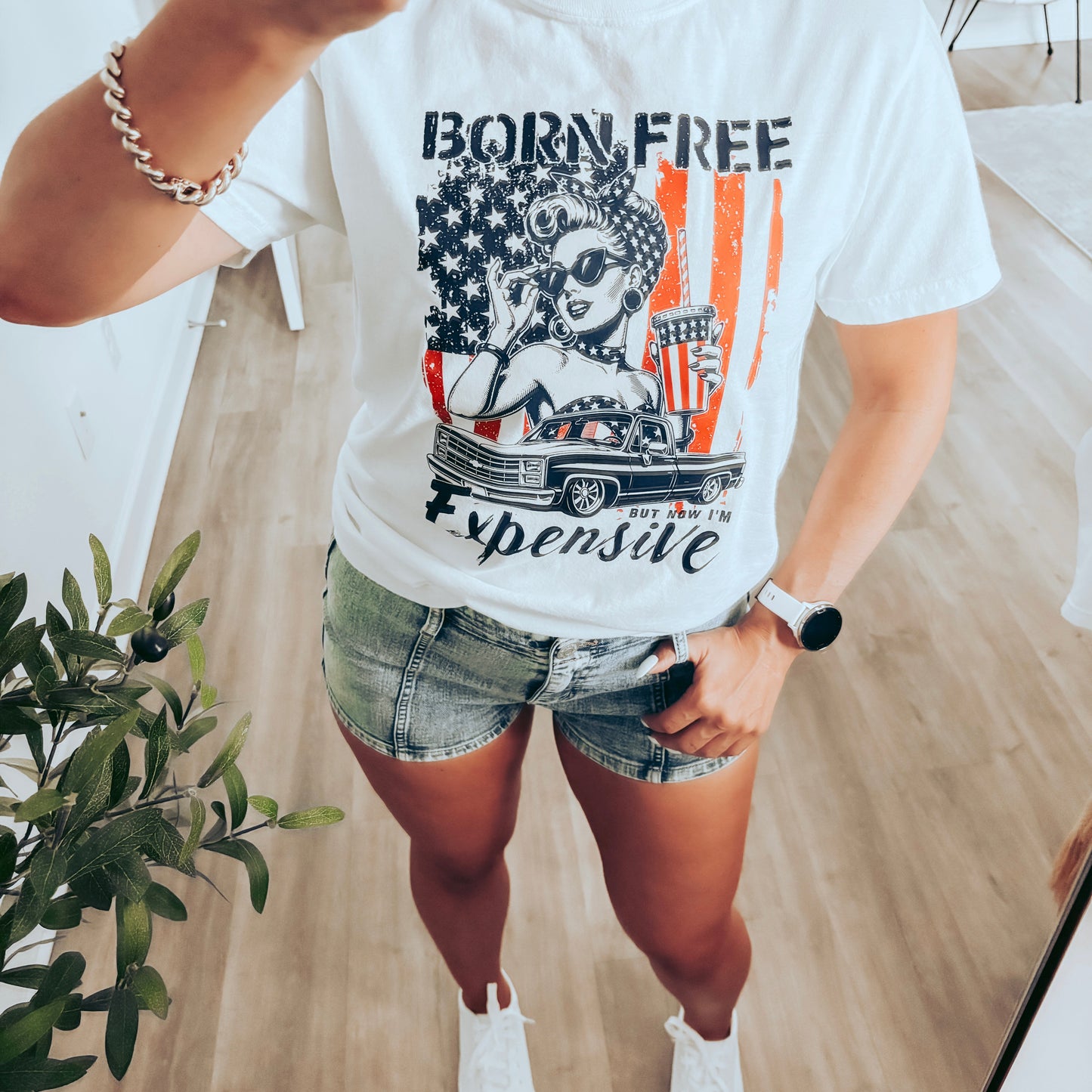 Person wearing a white t-shirt with graphic design and text, standing indoors.