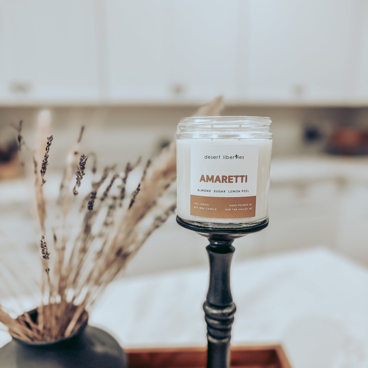 Candle labeled 'Amaretti' on a stand with decorative elements in the background