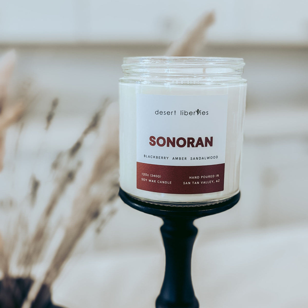 Candle jar labeled 'Sonoran' by Desert Libellulaes with a blurred background