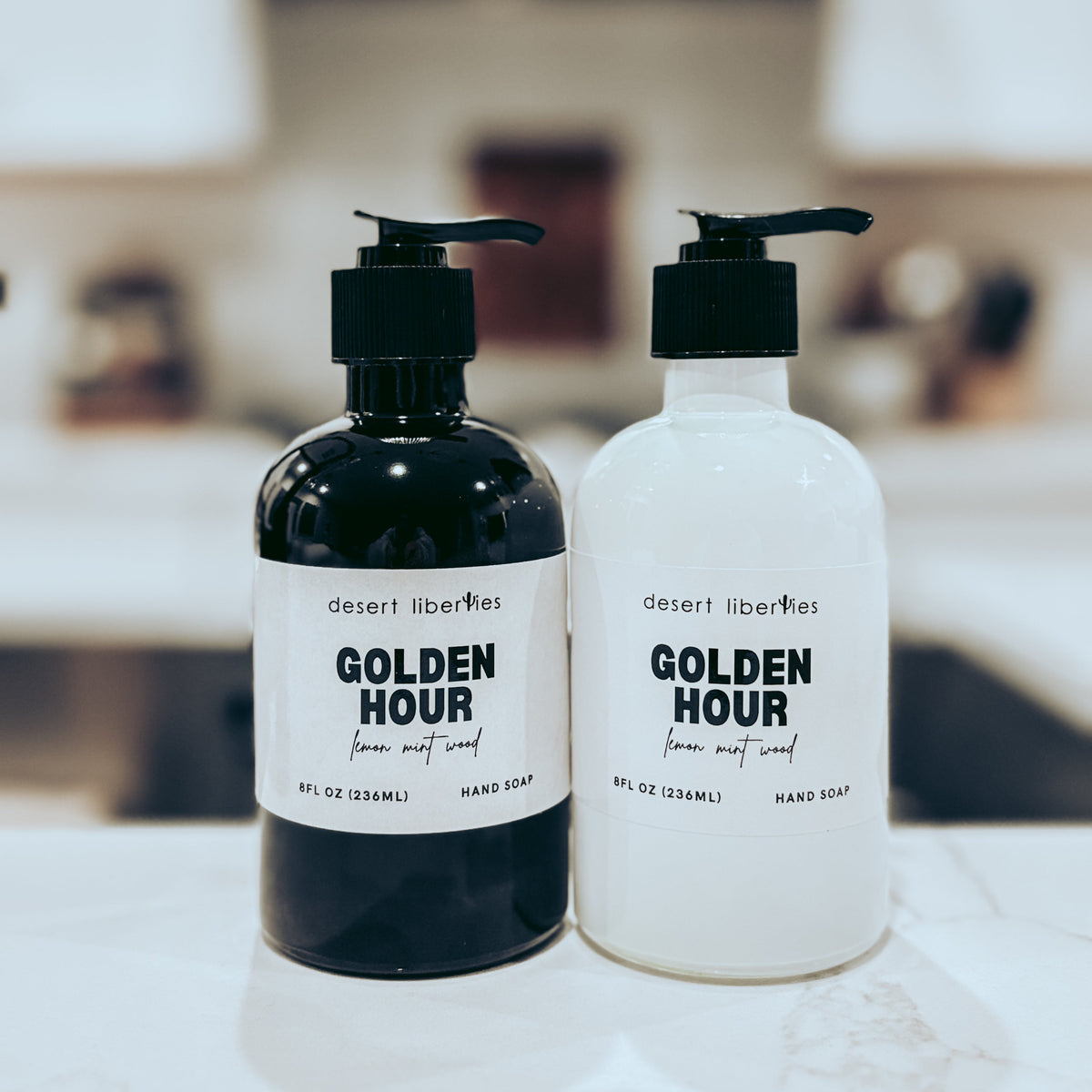 Two bottles of 'Golden Hour' hand soap on a surface with a blurred background
