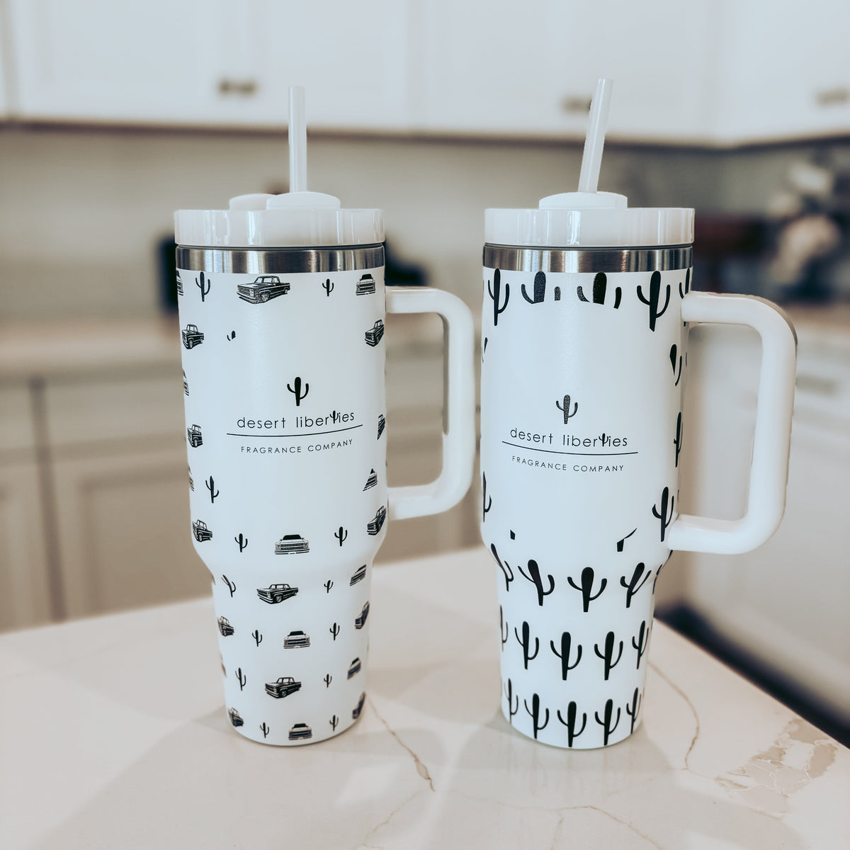 Two insulated travel mugs with cactus design on a kitchen counter