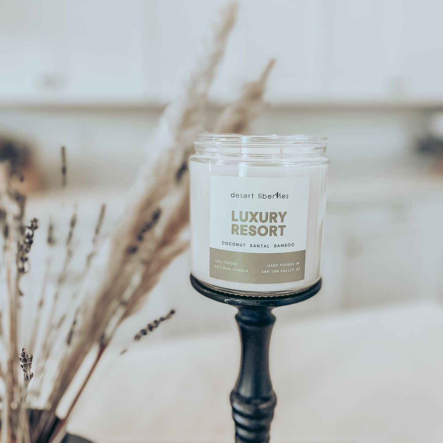 Candle labeled 'Luxury Resort' on a stand with decorative elements in the background
