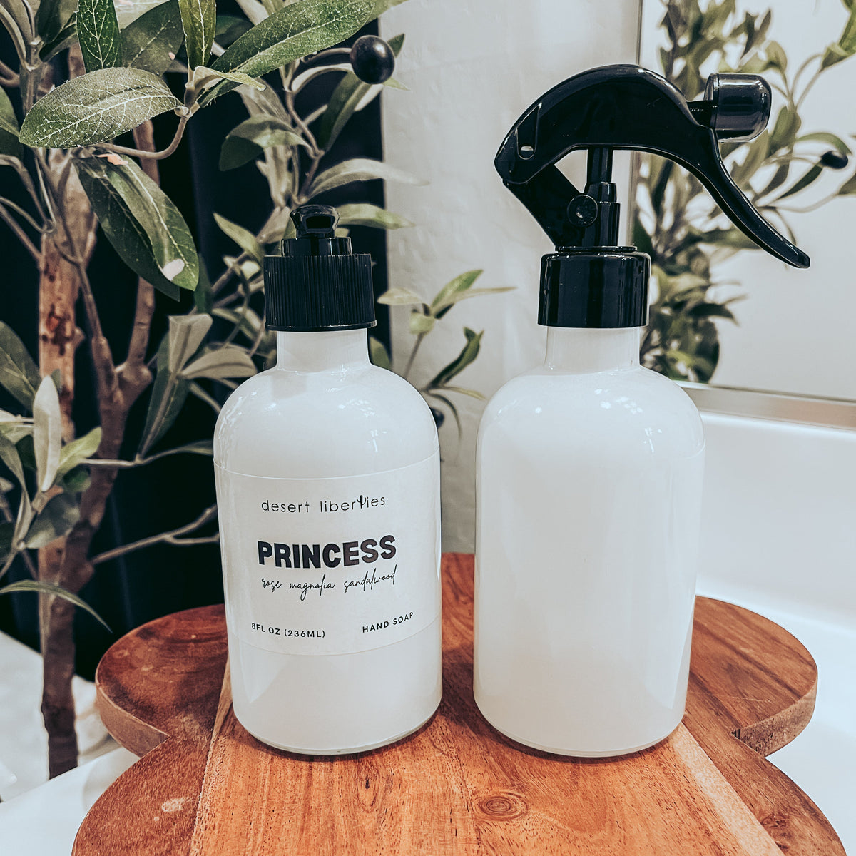 Soap bottle next to an unlabeled spray bottle on a wood surface and olive tree in the background.