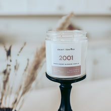 Load image into Gallery viewer, Candle with a label on a black holder against a neutral background