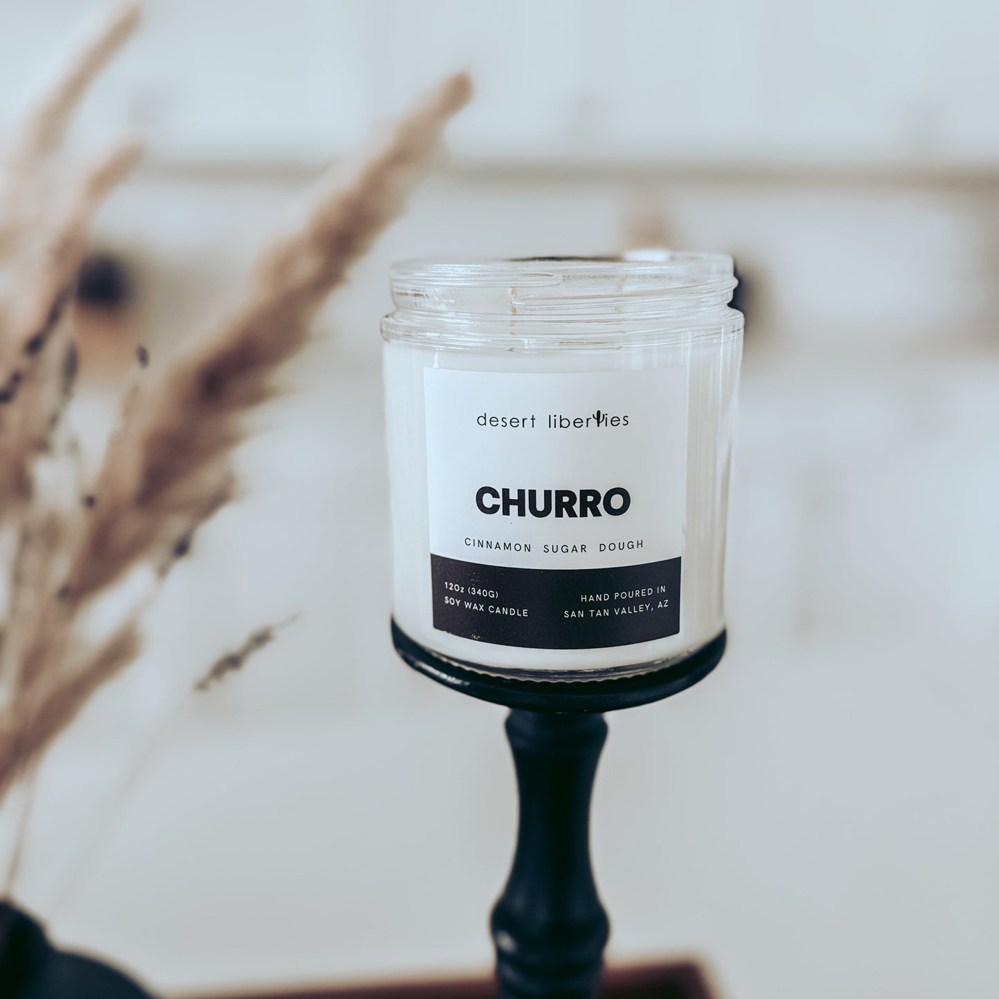 Candle labeled "Churro" on a black candlestick and a blurred kitchen background.