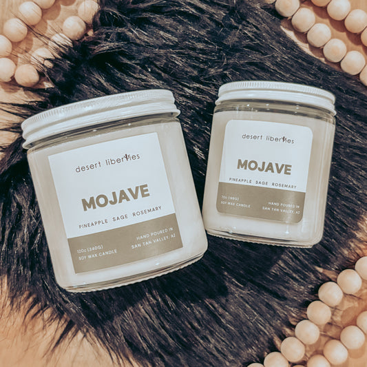 Two 'Mojave' candles by Desert Lilacs on a fur surface with beads around.
