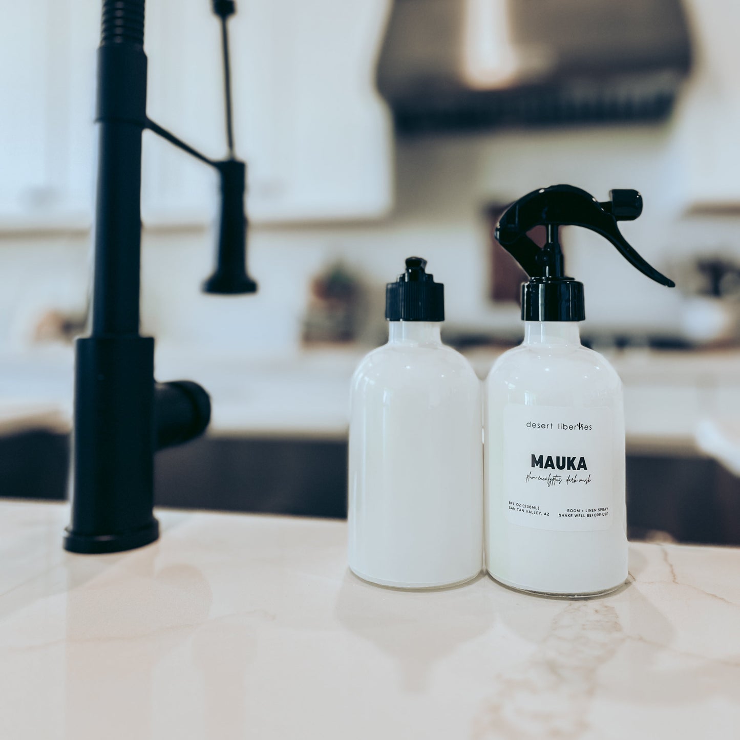 Two bottles labeled 'MAUKA' on a kitchen counter with a black faucet in the background.