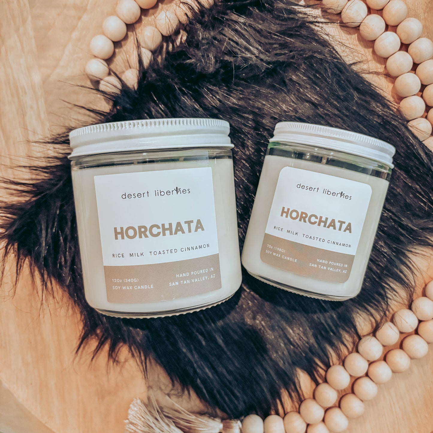 Two horchata candles on a black fur and wood background.