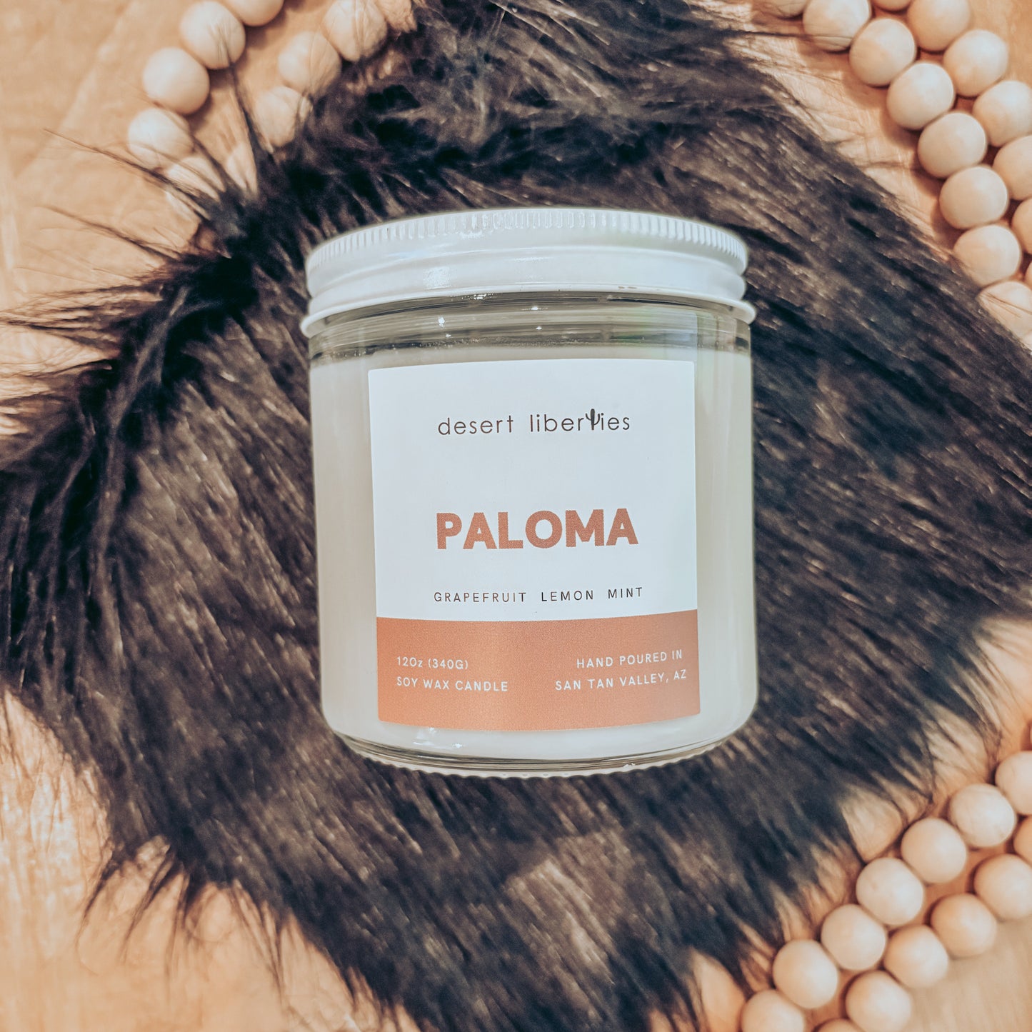 Candle labeled Paloma on a black fur and wood surface.