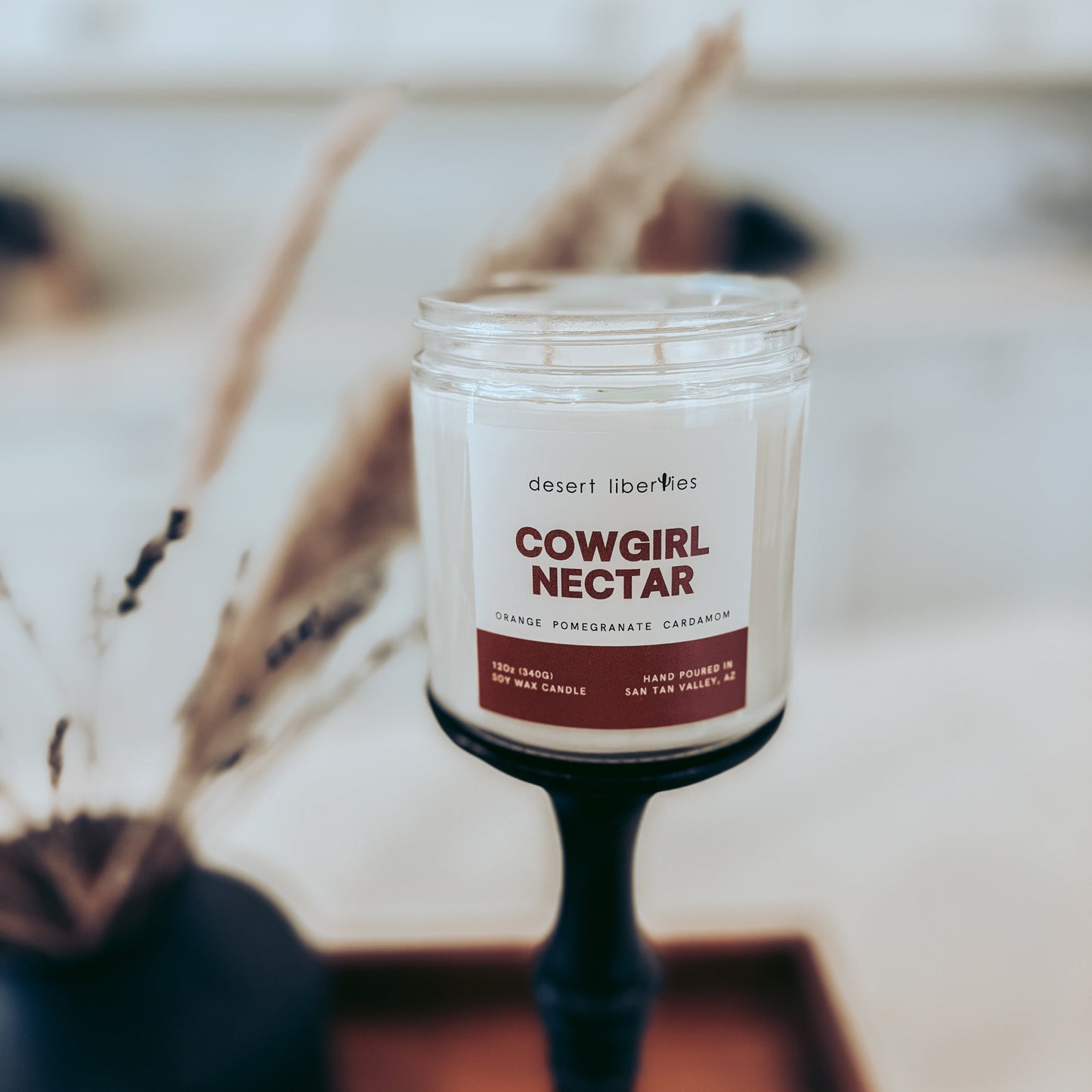 Candle labeled 'Cowgirl Nectar' on a blurred background