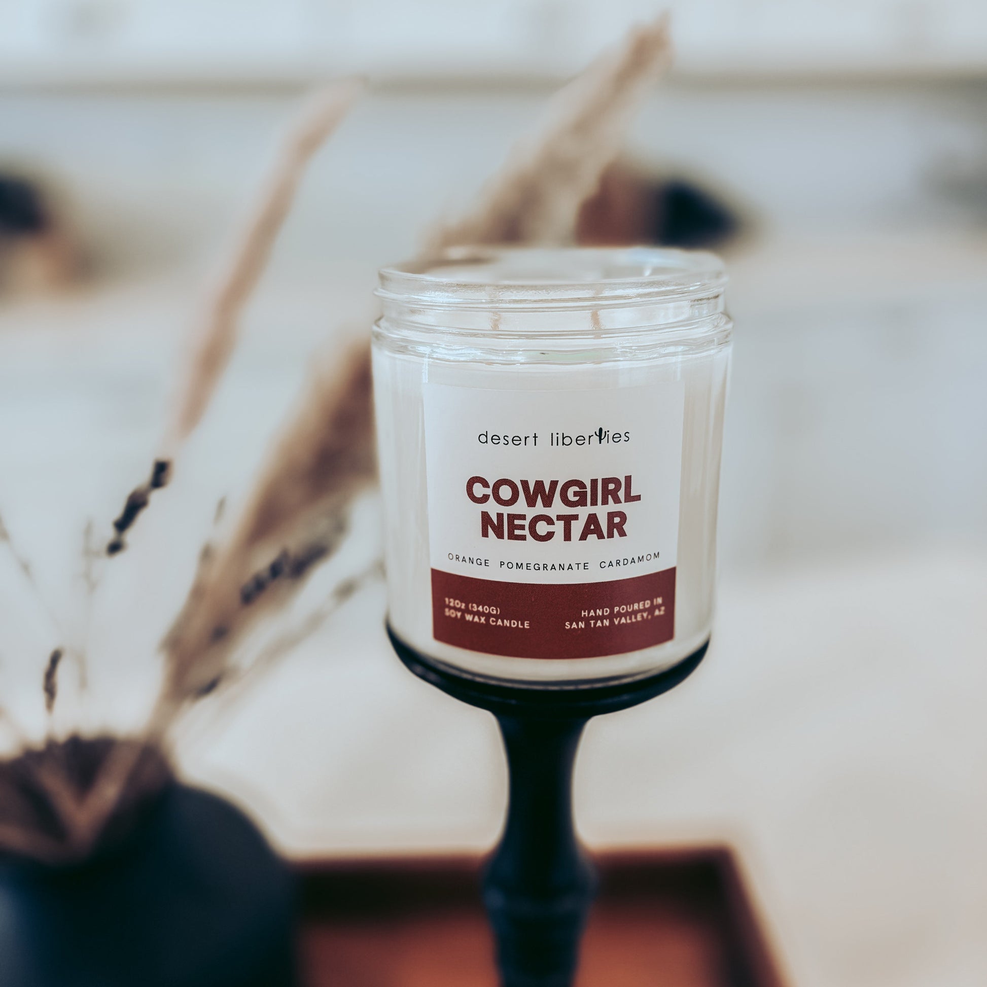 Candle labeled 'Cowgirl Nectar' on a blurred background