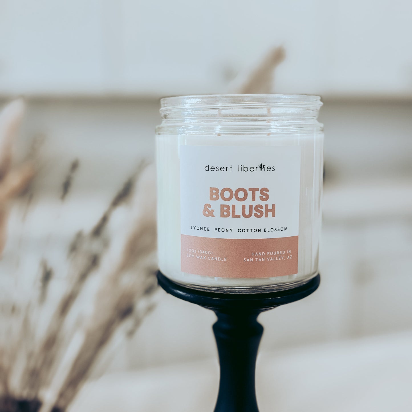 Candle labeled 'Boots & Blush' on a blurred background