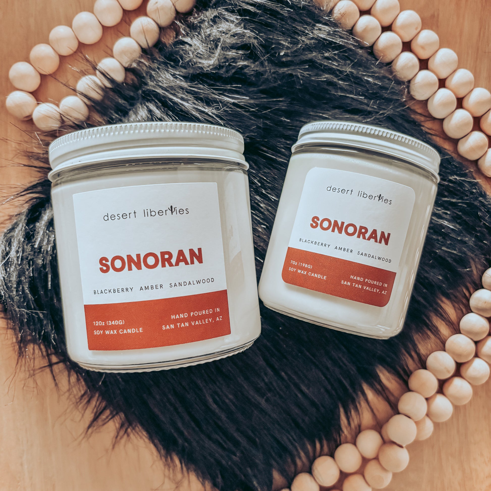 Two Sonoran candles by Desert Liberties on a wooden surface with decorative elements.