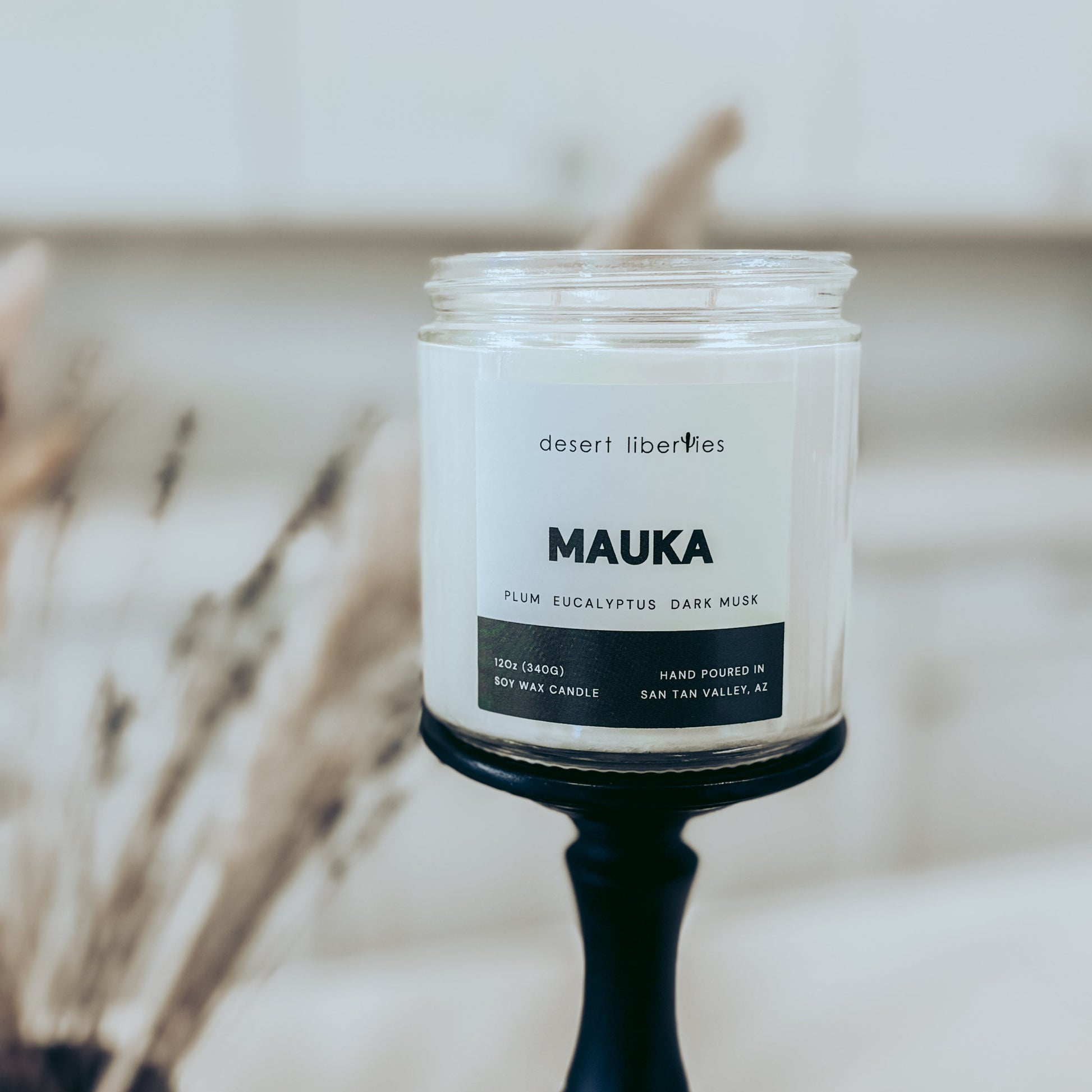 Candle with 'MAUKA' label on a blurred background