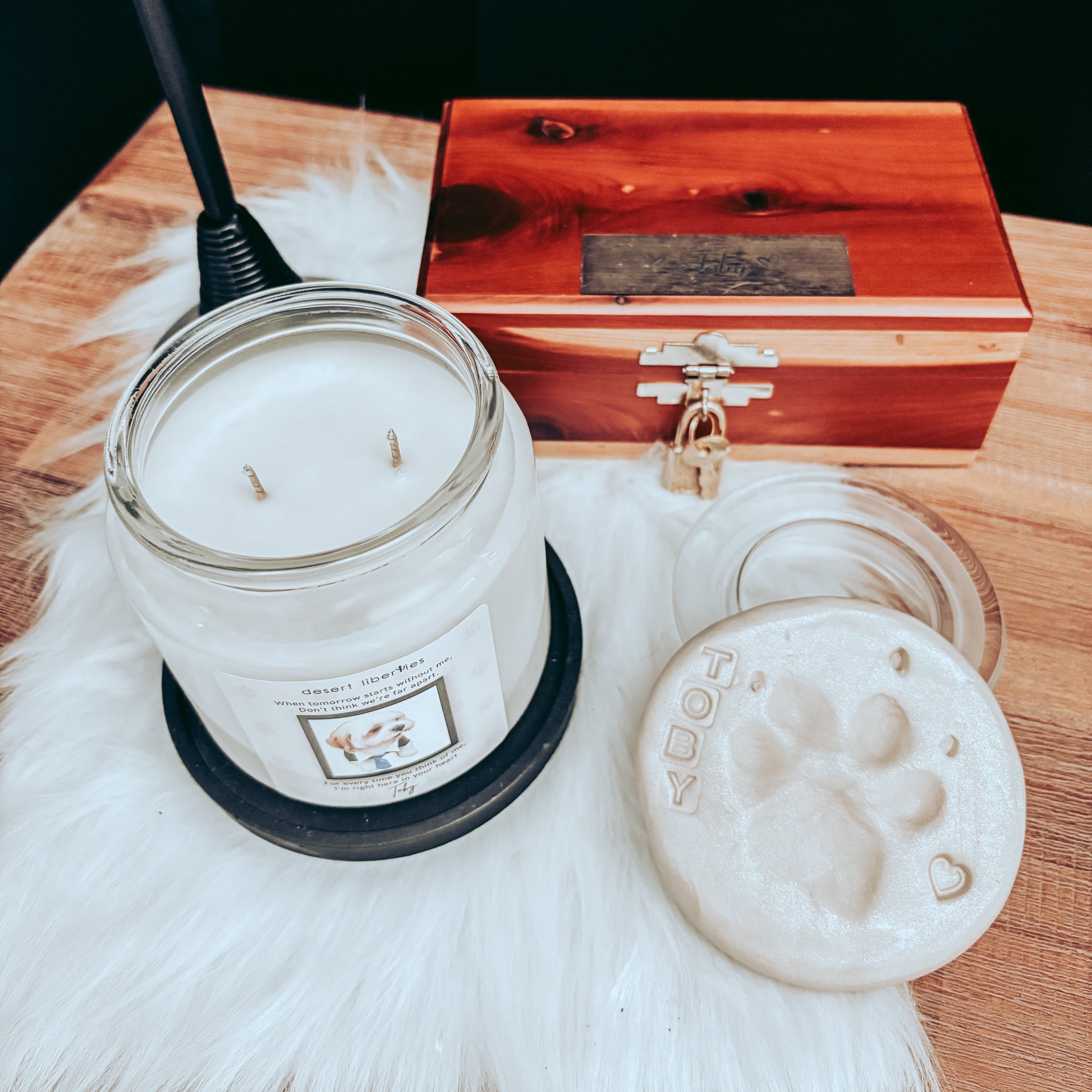Candle in a glass jar with a wooden box and paw print coaster on a fur surface