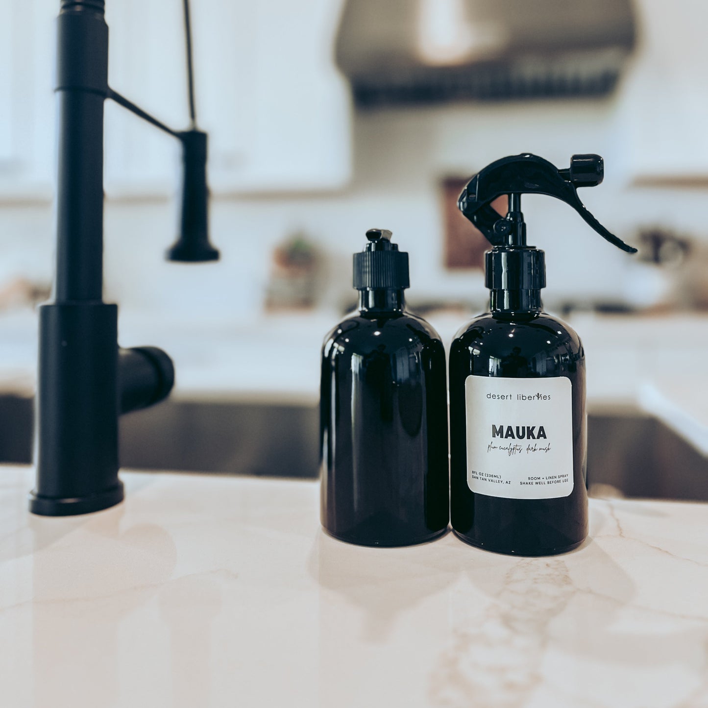 Two black bottles labeled 'MAUKA' on a kitchen counter with a modern faucet in the background.