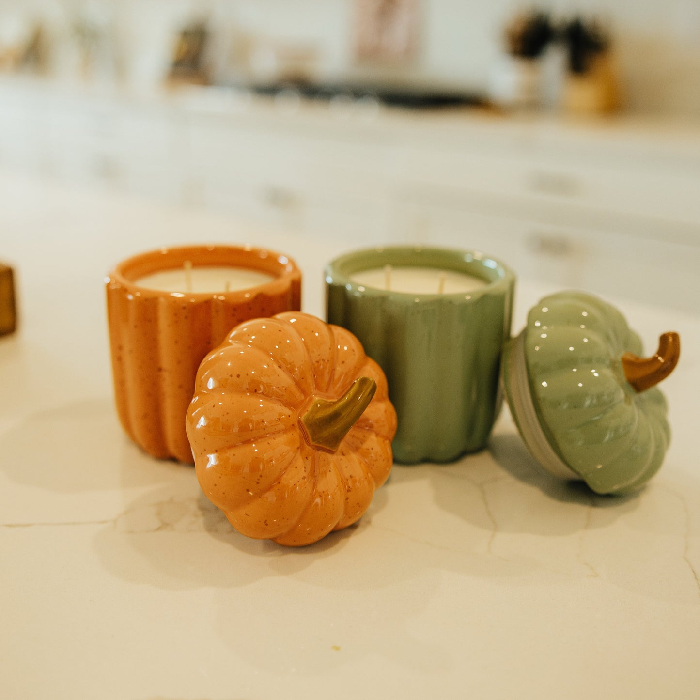 Decorative candles shaped like pumpkins and gourds on a kitchen counter.