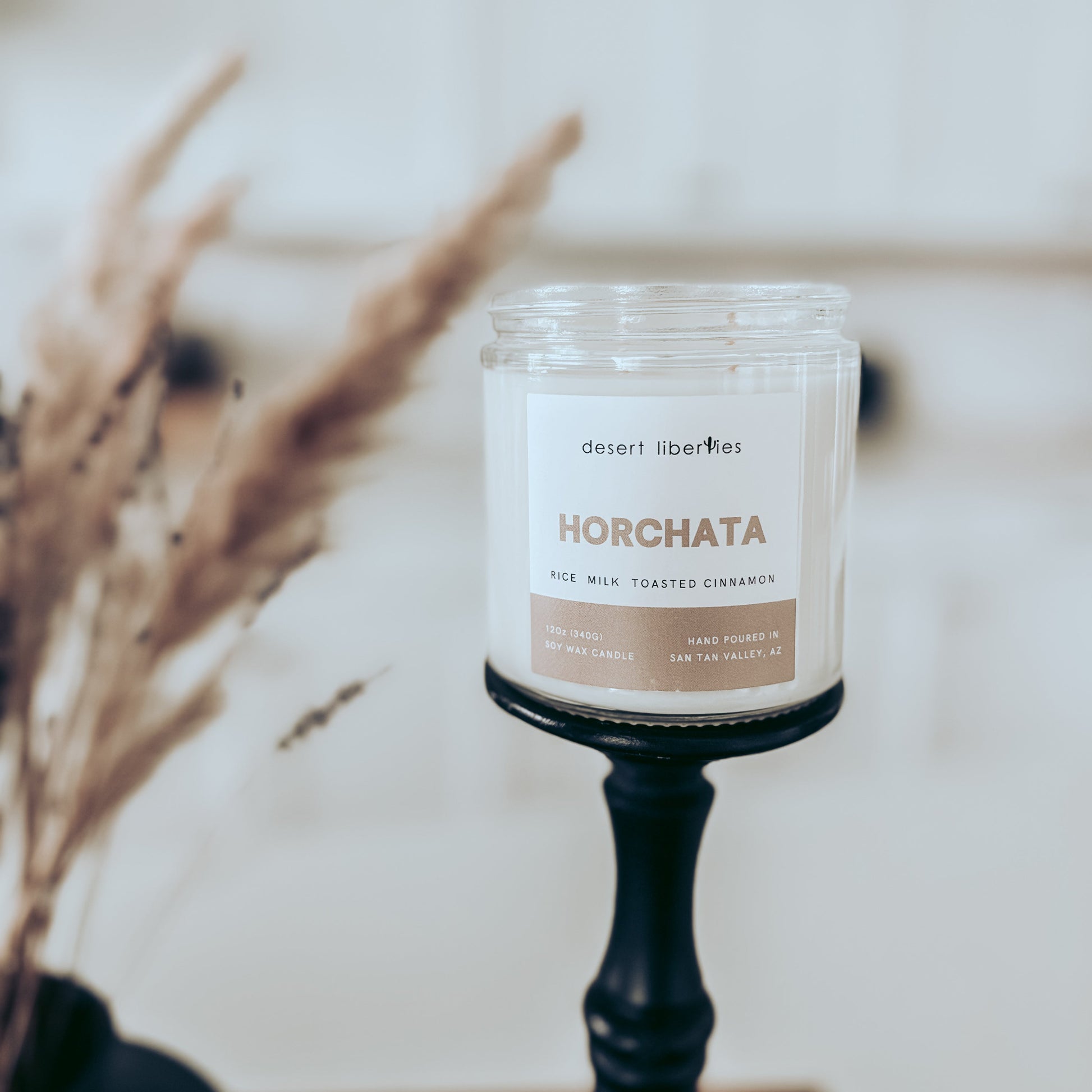 Candle labeled "horchata" on a black candlestick with blurred kitchen background.