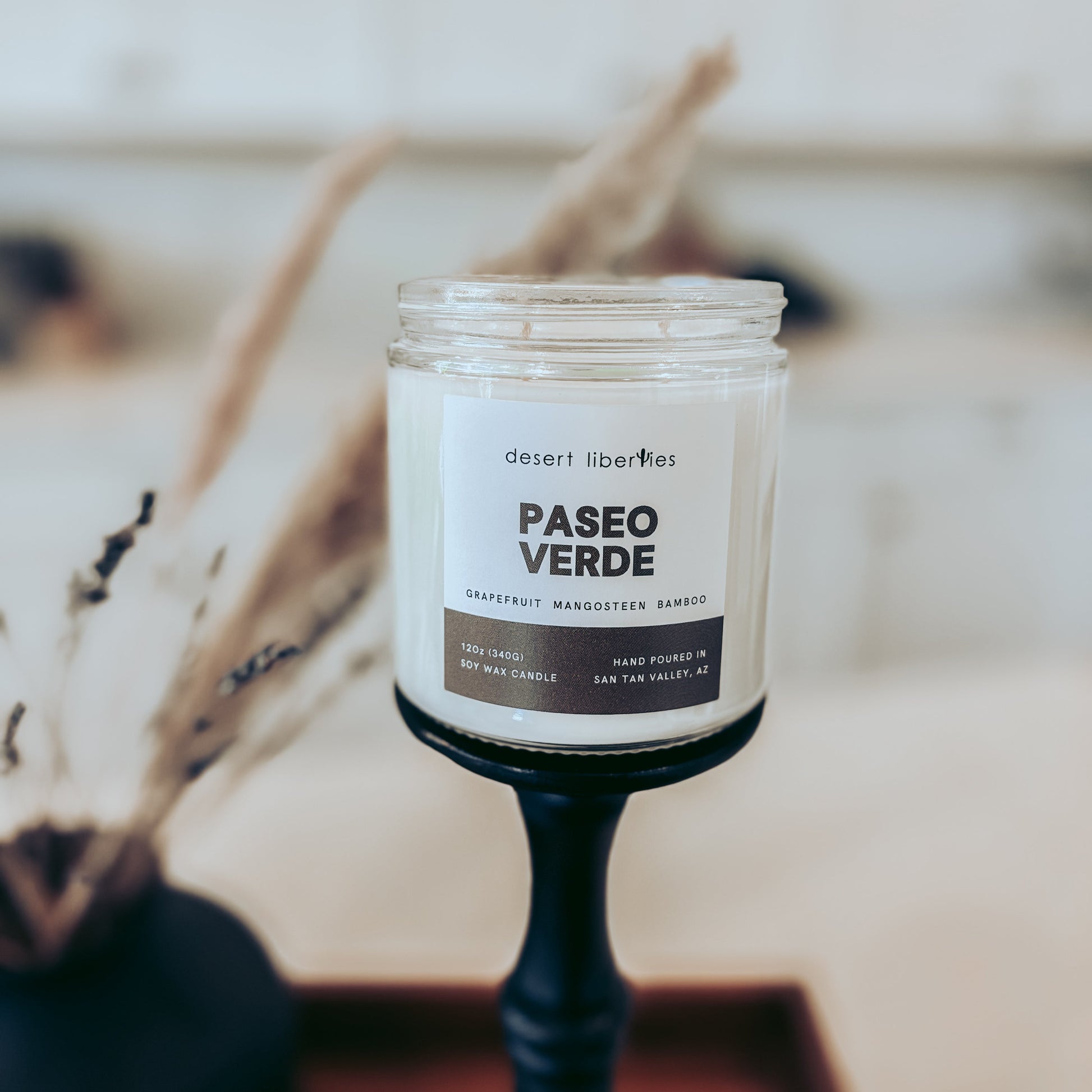Candle with 'Paseo Verde' label on a blurred background