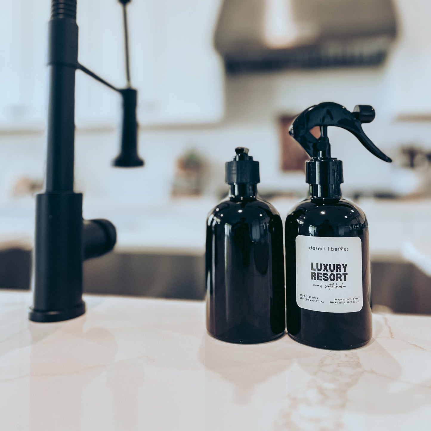 Two black bottles with spray nozzles on a kitchen counter.