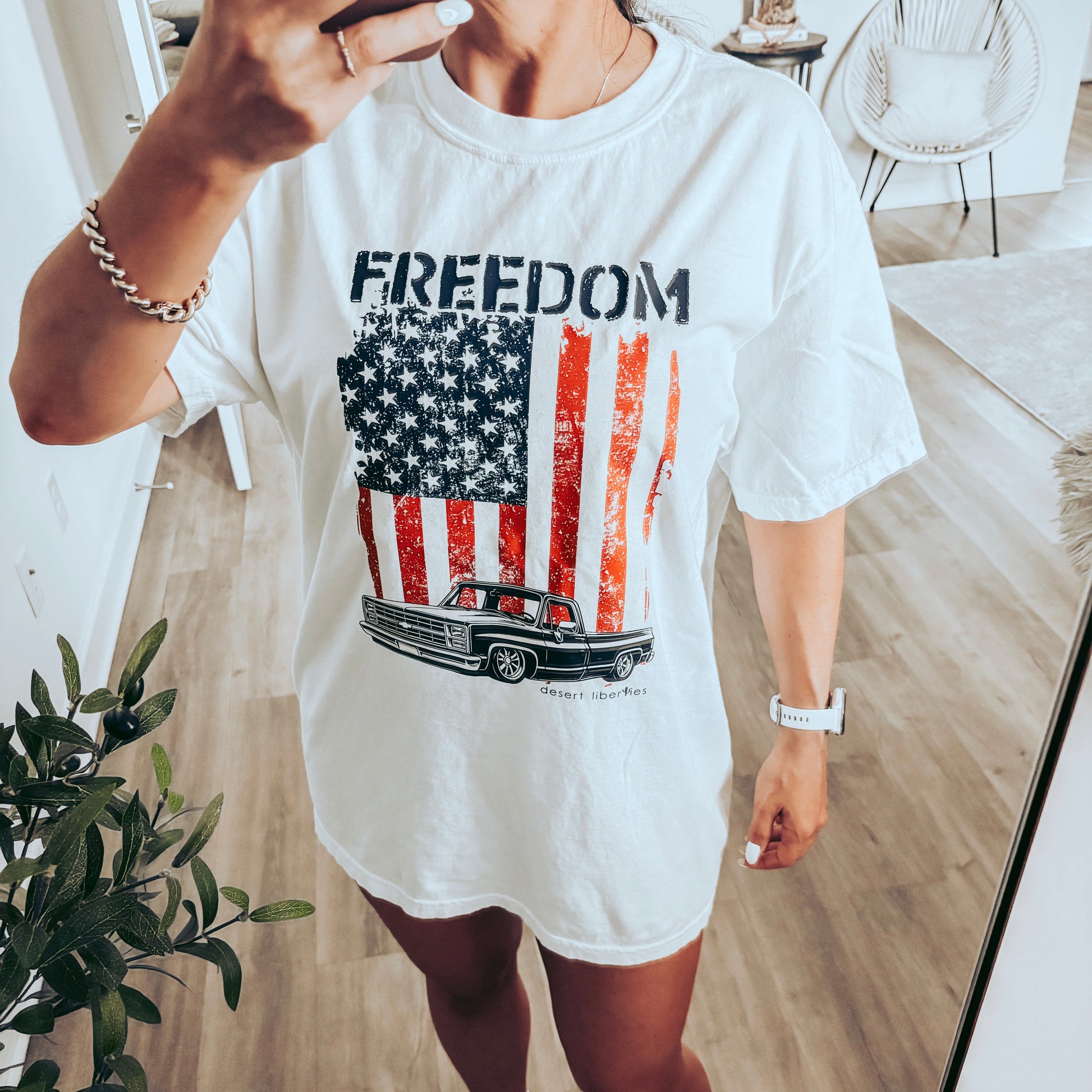 Person wearing a white t-shirt with an American flag graphic and 'FREEDOM' text, standing indoors.