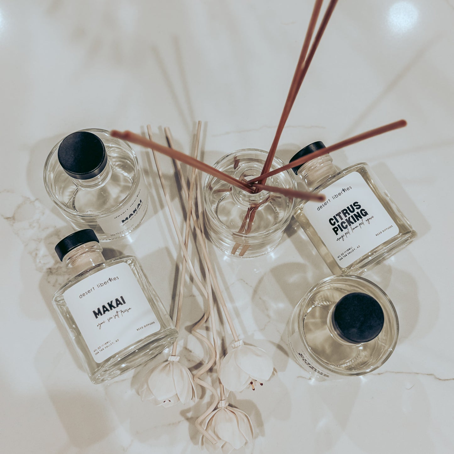 Four diffuser bottles with reeds on a light surface
