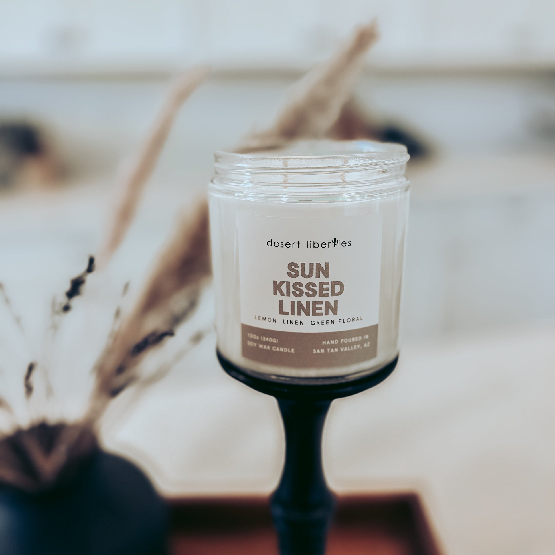 Candle labeled 'Sun Kissed Linen' on a blurred background