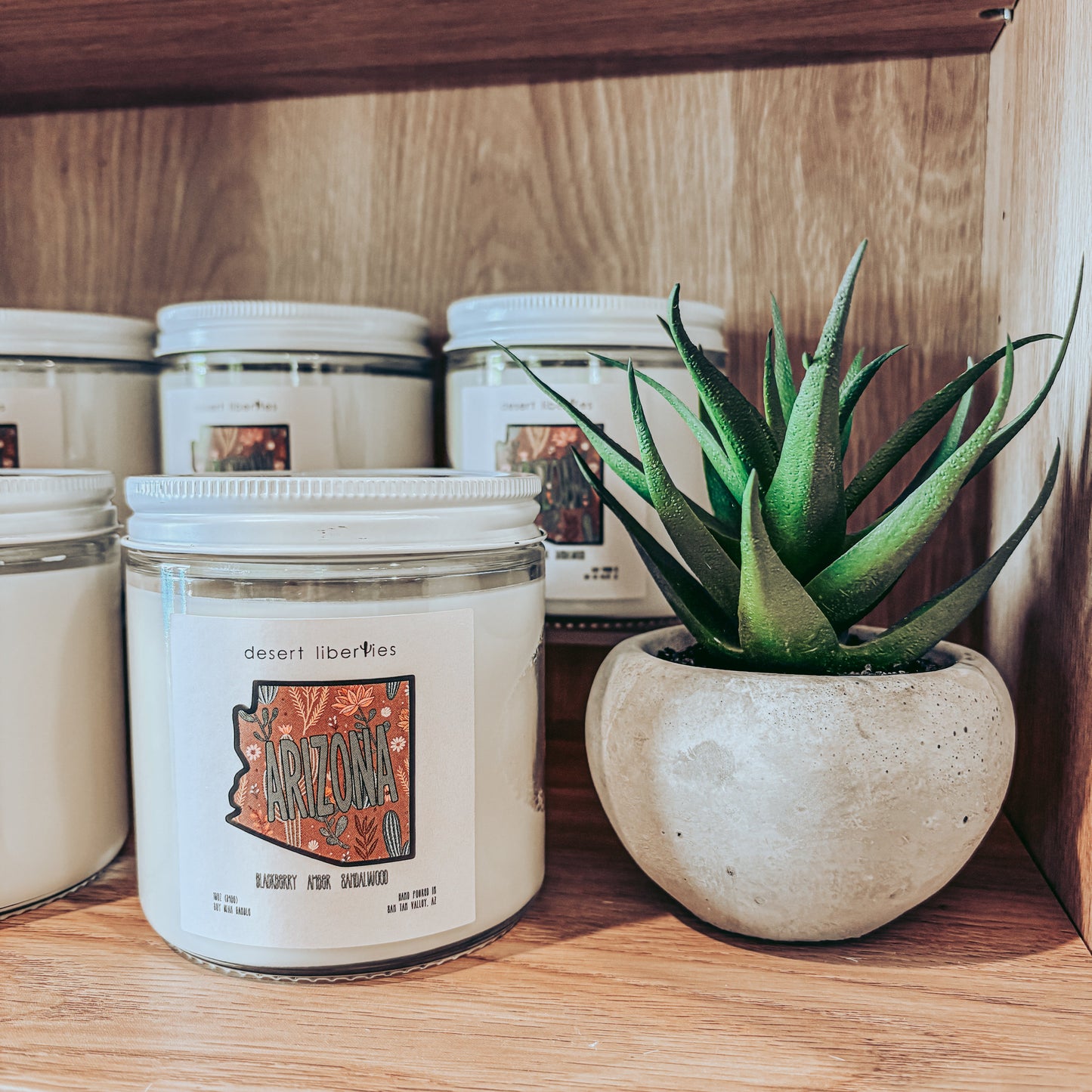 Candle jars with a plant on a wooden shelf