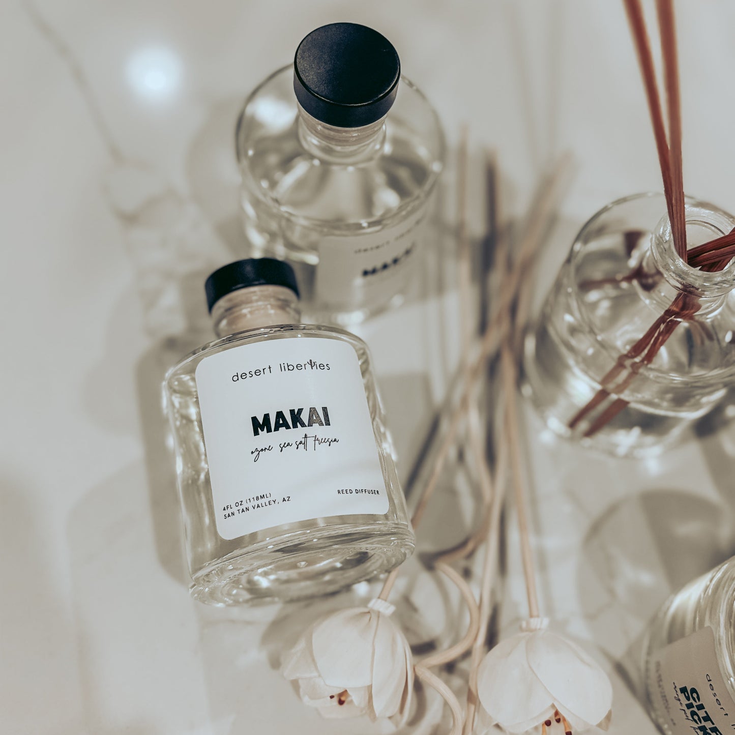 Two clear bottles with black caps and labels on a neutral background