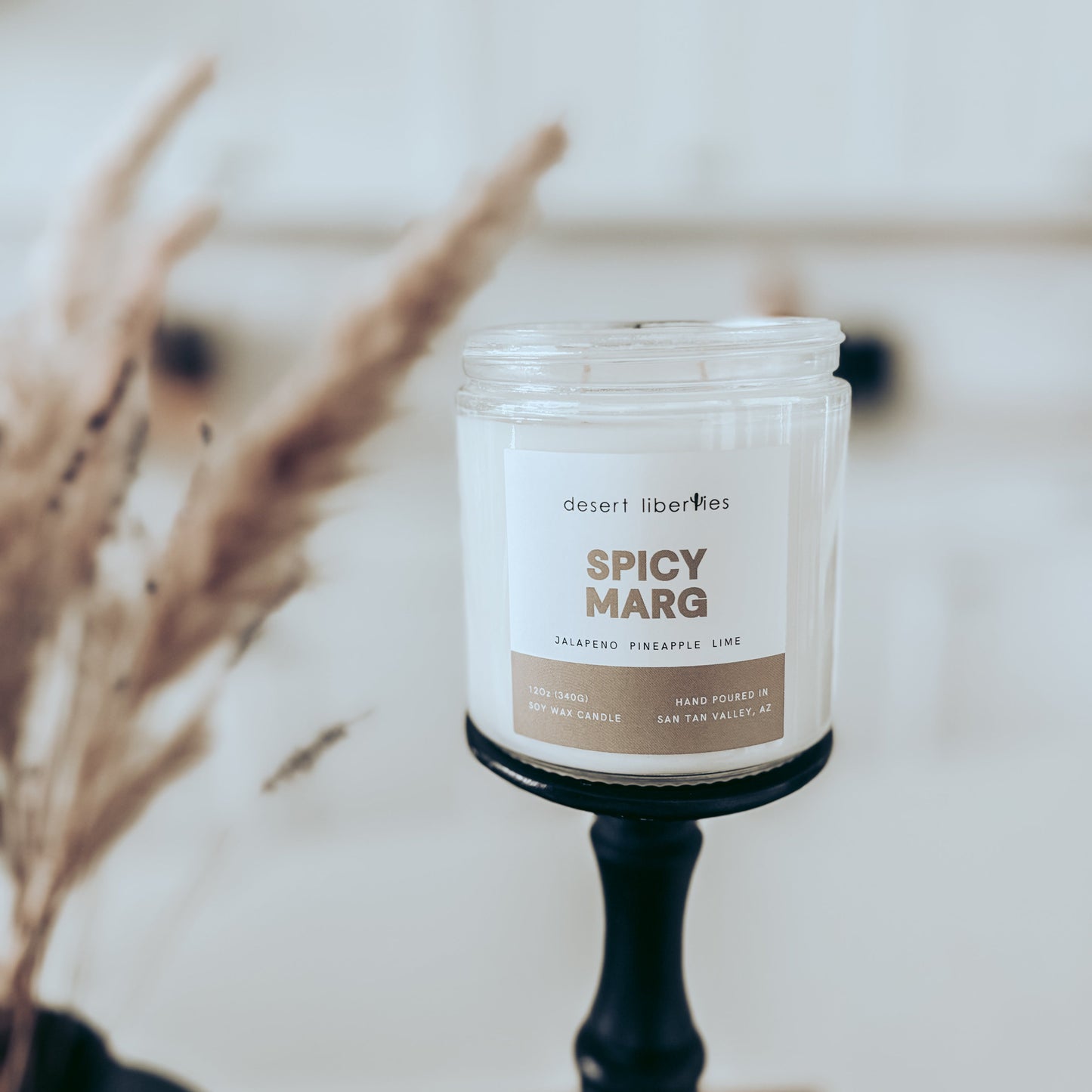 Candle labeled 'Spicy Marg' on a stand with a blurred background
