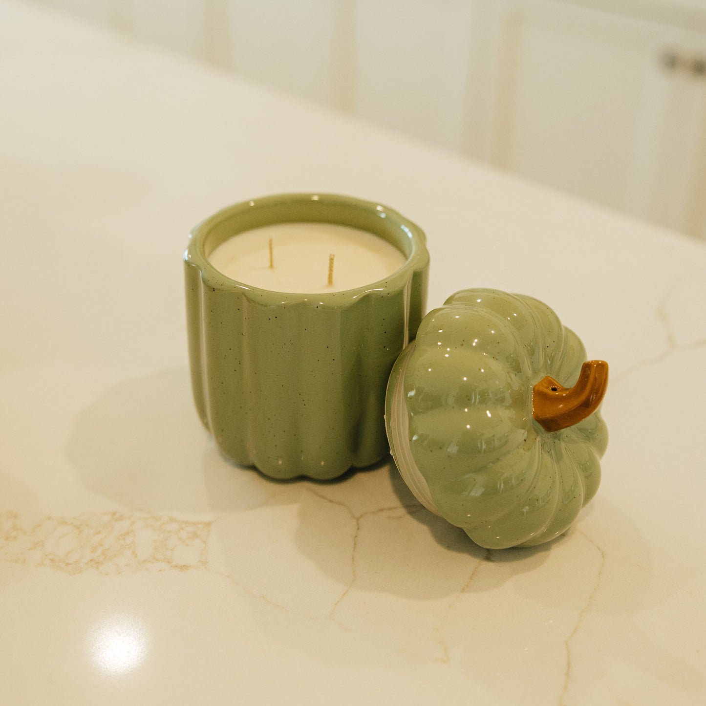 Green ceramic pumpkin-shaped candle on a kitchen counter
