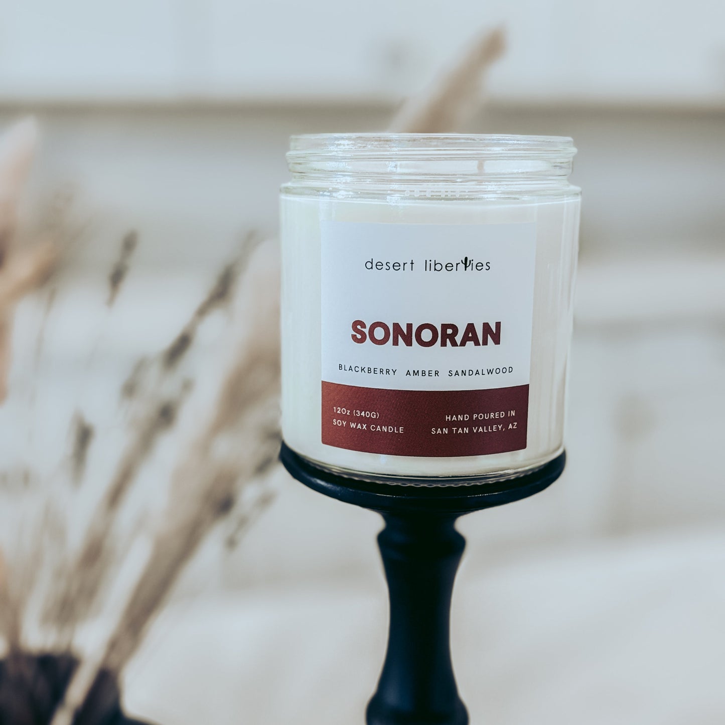 Candle jar labeled 'Sonoran' by Desert Libellulaes with a blurred background