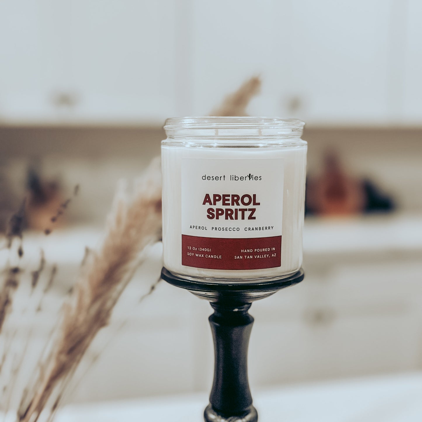 Candle labeled 'Aperol Spritz' on a stand with a blurred background