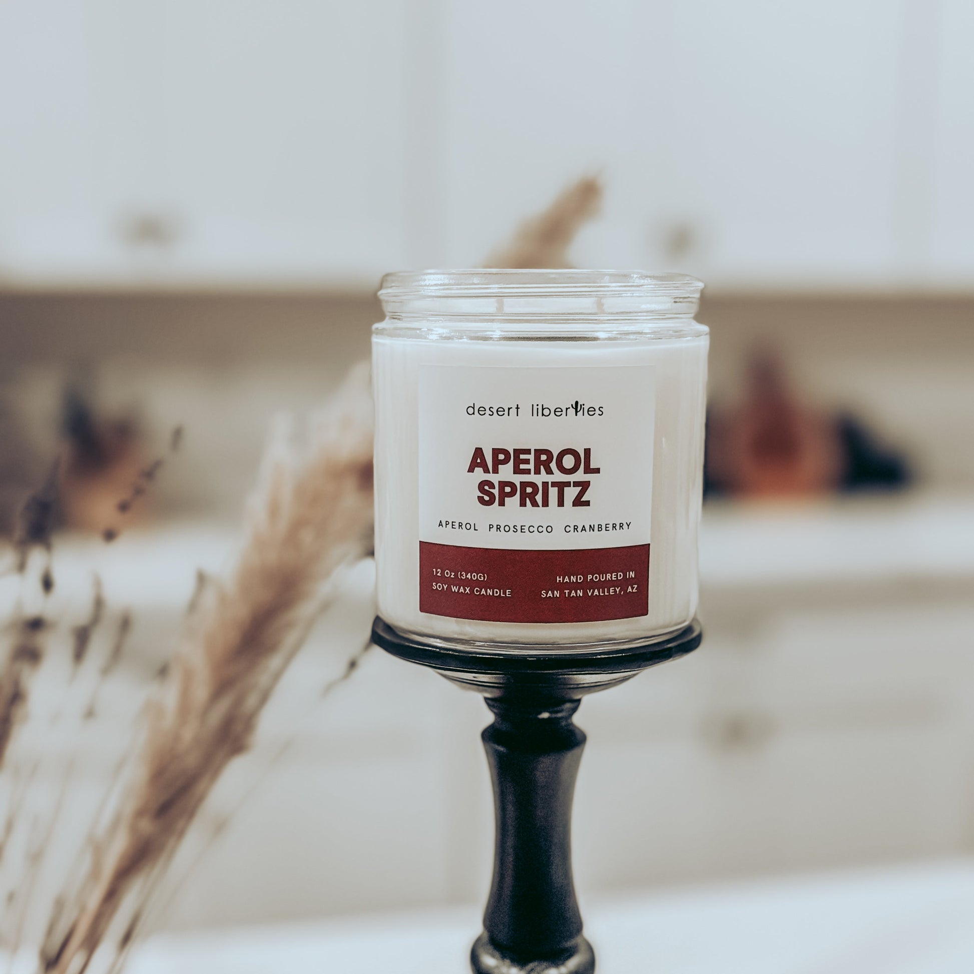 Candle labeled 'Aperol Spritz' on a stand with a blurred background