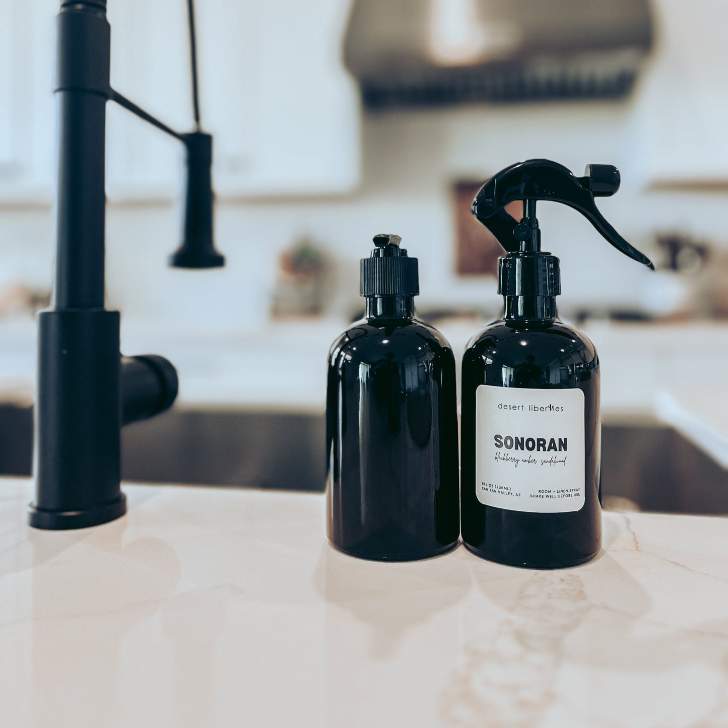 Two black bottles labeled 'Sonoran' on a kitchen counter with a modern faucet in the background.