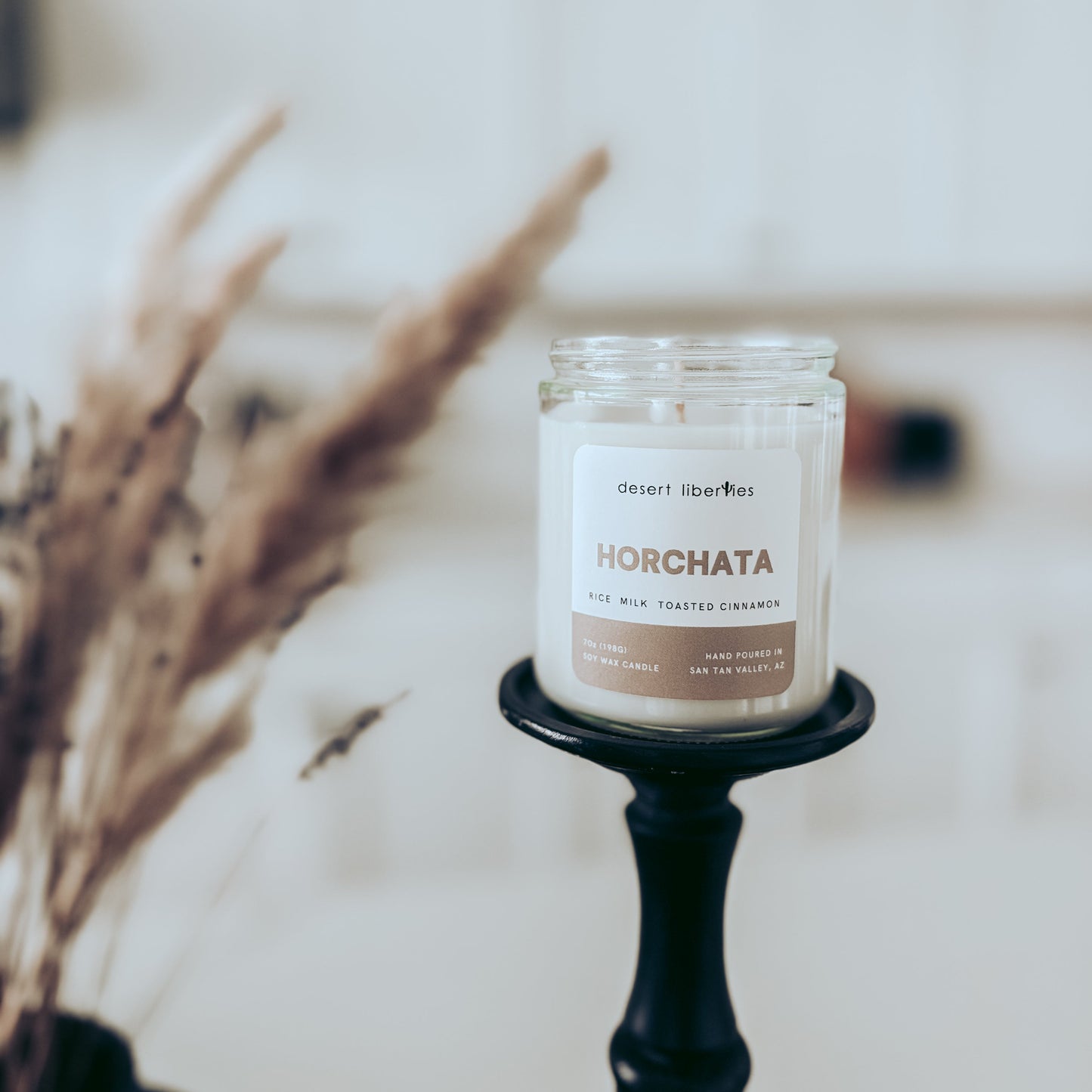 Candle labeled 'Horchata' on a black holder with a blurred background
