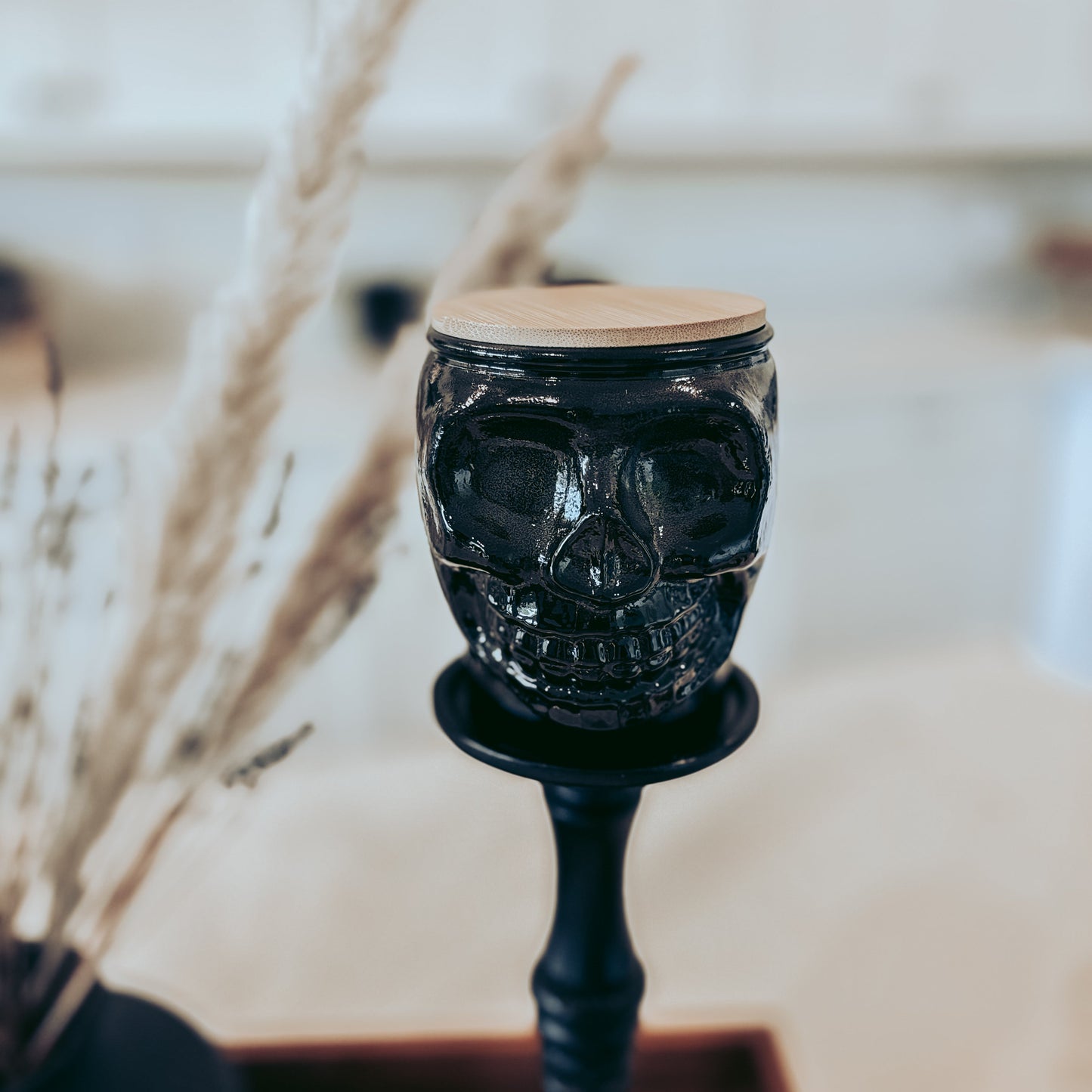 Black skull-shaped candle holder on a stand with a blurred background