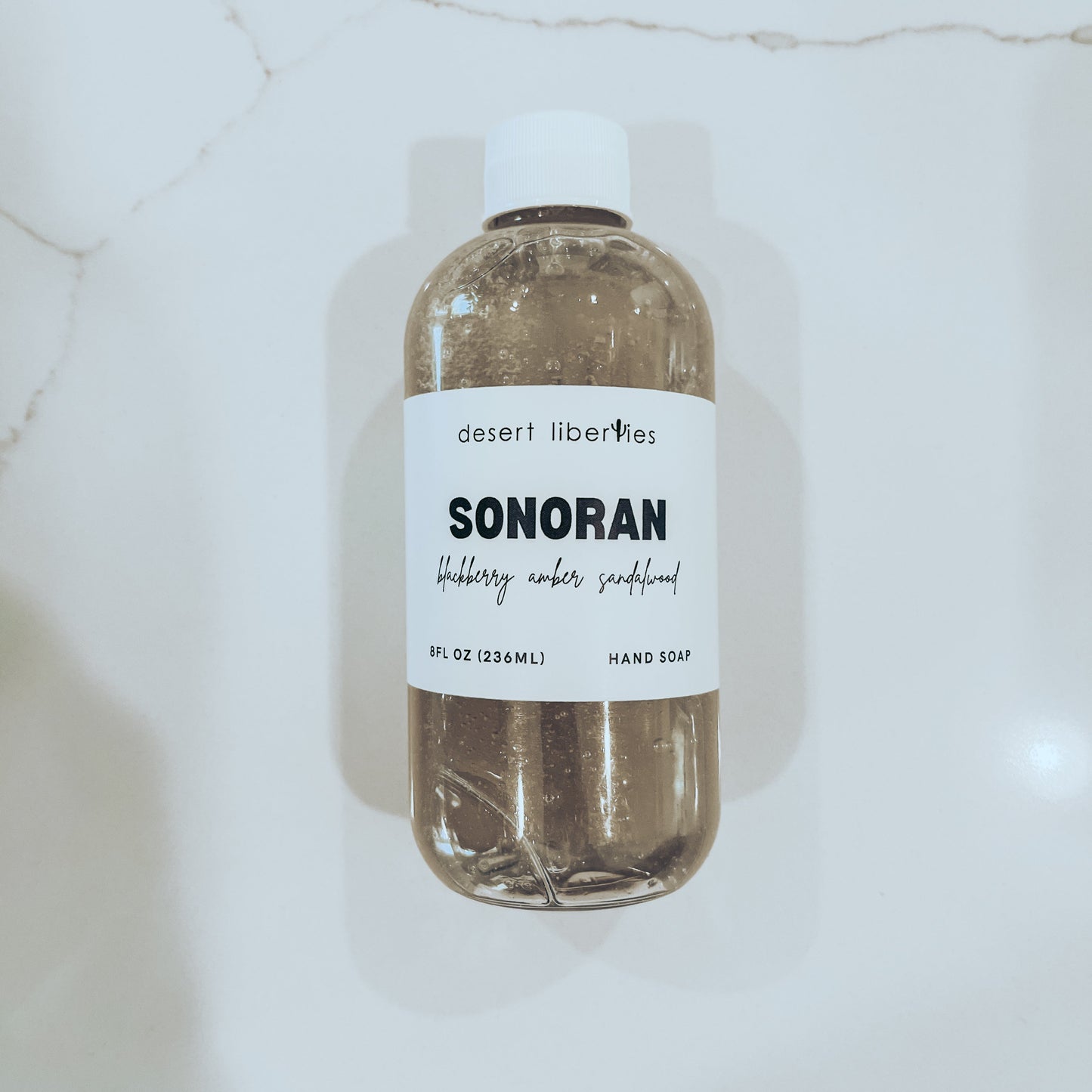 Bottle on a marble surface filled with soap and labeled. 