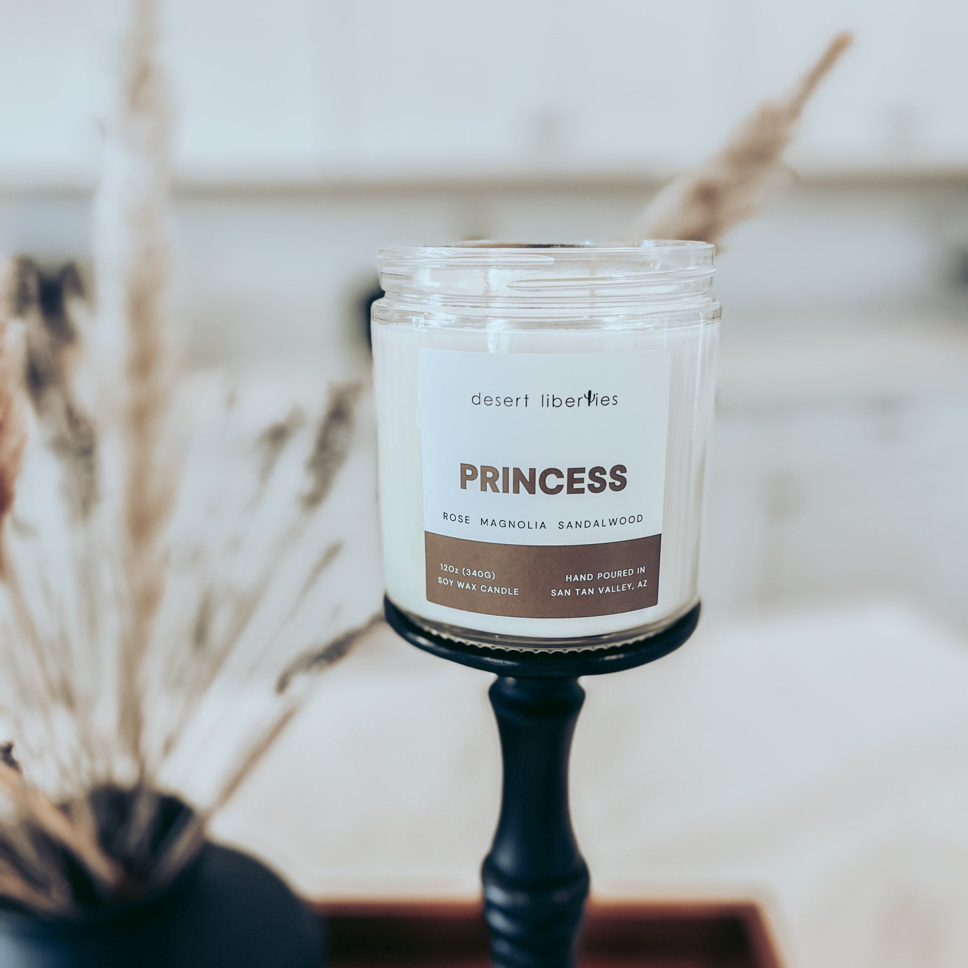 Candle labeled 'Princess' on a black holder with a blurred background