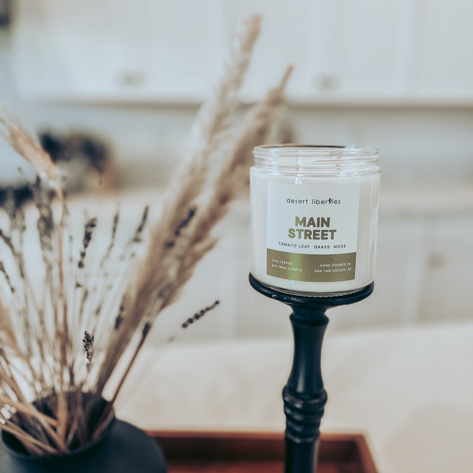 Candle labeled 'Main Street' on a stand with decorative elements in the background