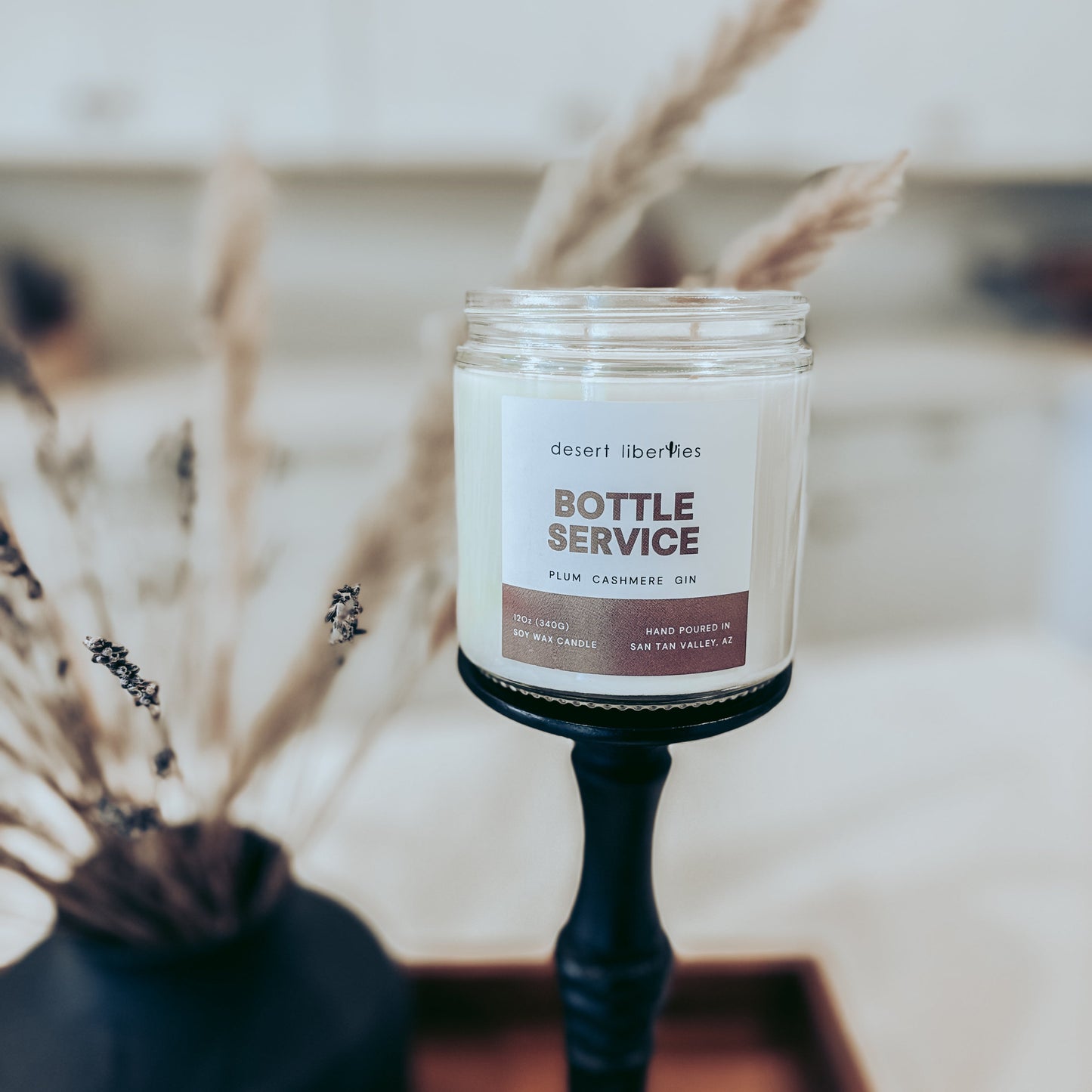 Candle labeled 'Bottle Service' on a stand with decorative elements in the background